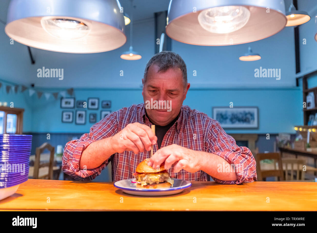 Ein Mann im t-shirt genießt die Signatur Burger an der Pig&Apple Cafe. Das Cafe ist in bescheidenen durch Natur, Monmouthshire, Wales. Stockfoto