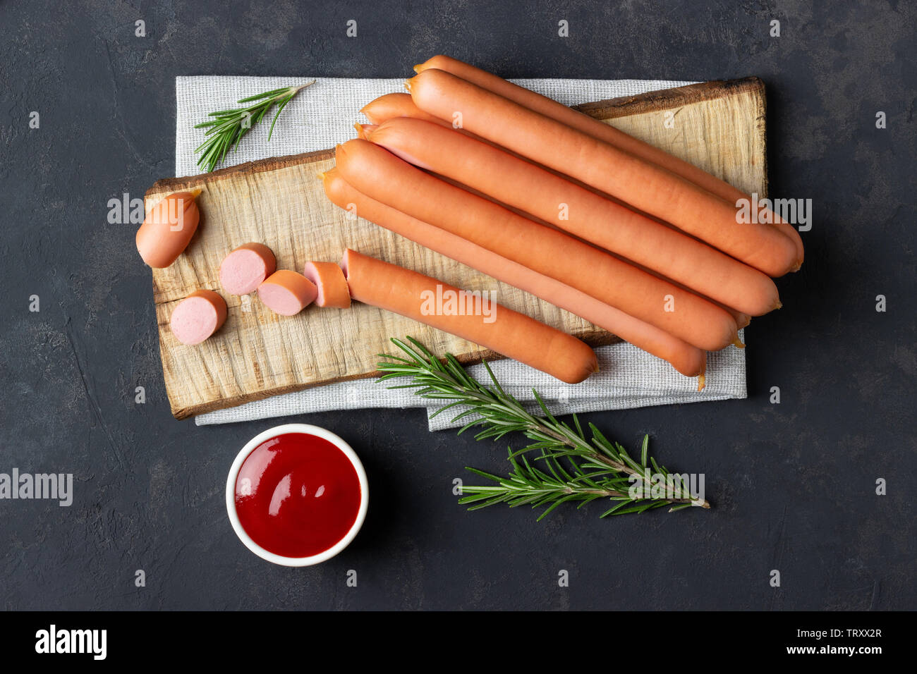 Raw Frankfurter Würstchen mit Ketchup auf Schneidebrett. Ansicht von oben. Stockfoto
