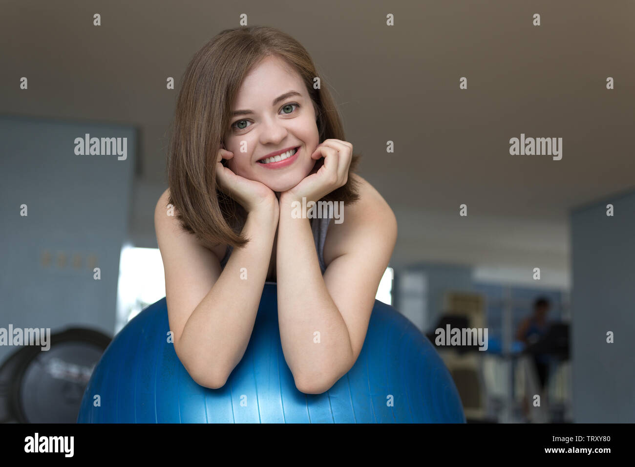 Lächelnden jungen kaukasischen Frau Mädchen auf Blau Gymnastikball im Fitnessstudio, Training oder Yoga Pilates Übung Stockfoto