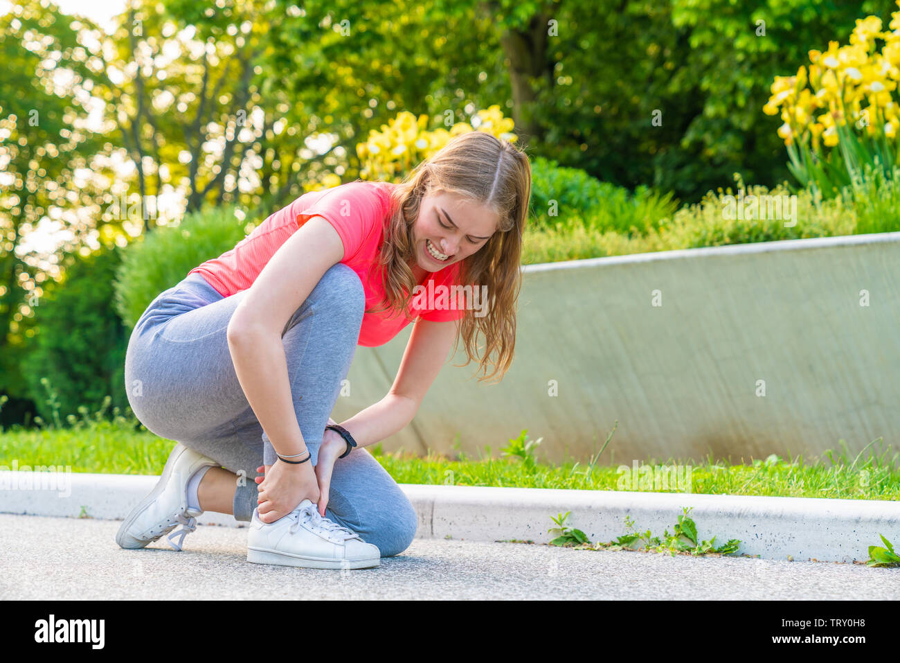 Eine jyoung ogger hat ihren Knöchel verletzt beim Gehen und hält es fest Stockfoto
