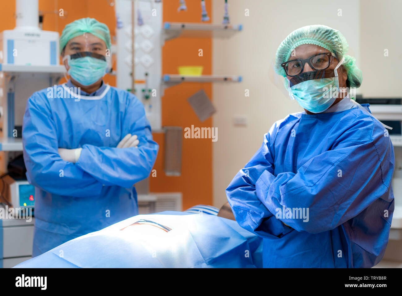 Chirurgen Team angebaut in Uniform und Maske arm Cross im Operationssaal. Op-Team die Vorbereitung für die Chirurgie in Betrieb. Stockfoto