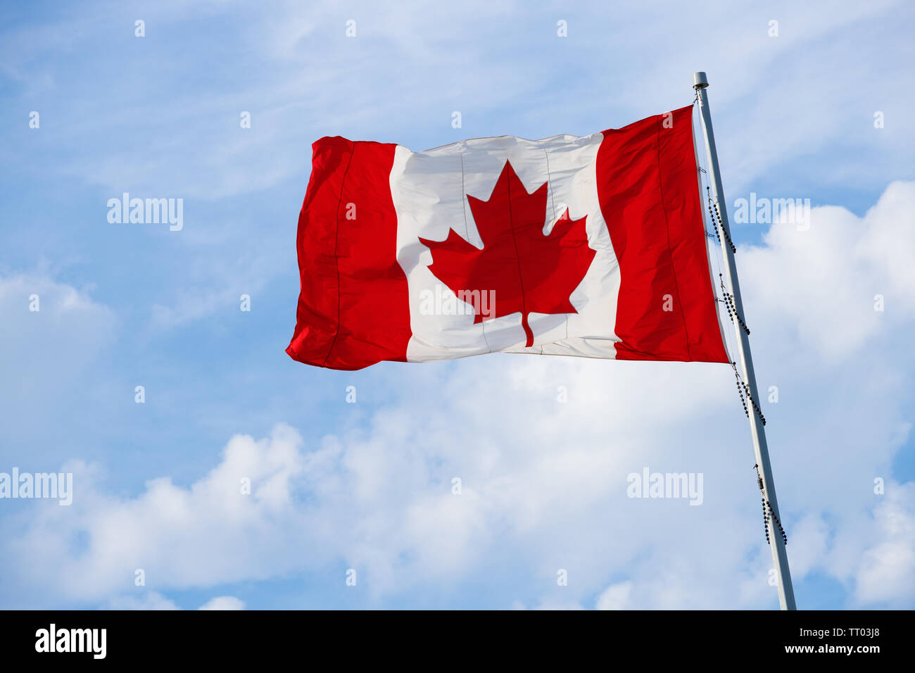 Kanadische Flagge auf der Pole in den Wind mit Wolken und blauer Himmel. Stockfoto
