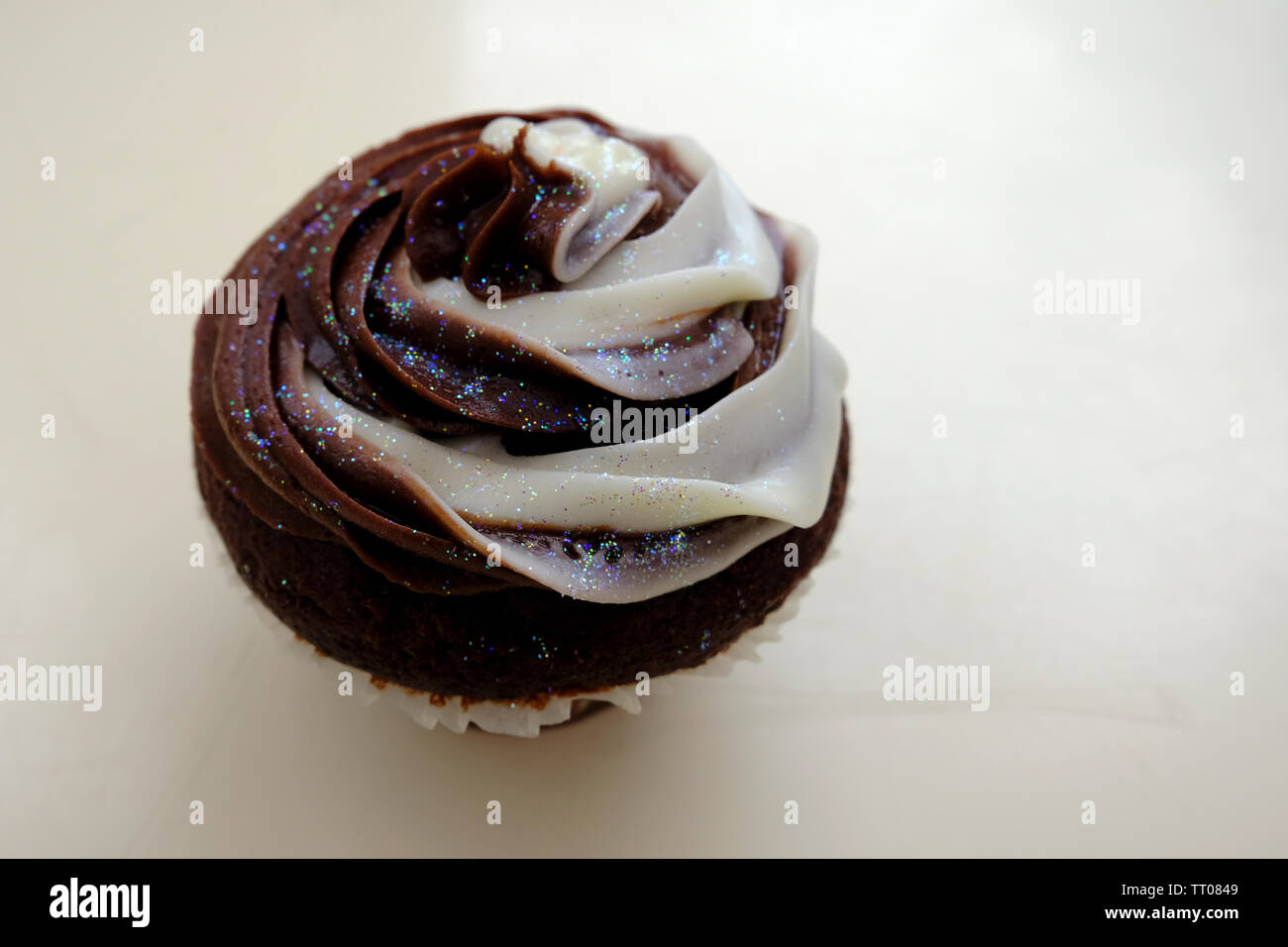 Chocolate Cupcake mit Vanille und Schokolade butter Puderzucker und gekrönt mit essbaren Glitter Stockfoto