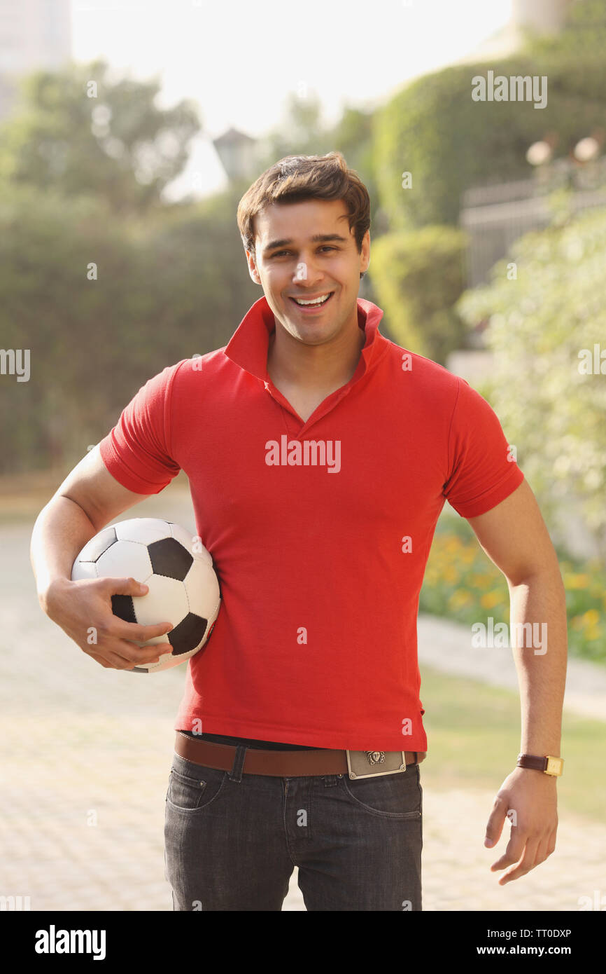 Mann hält einen Fußball unter dem Arm und lächelnd Stockfoto