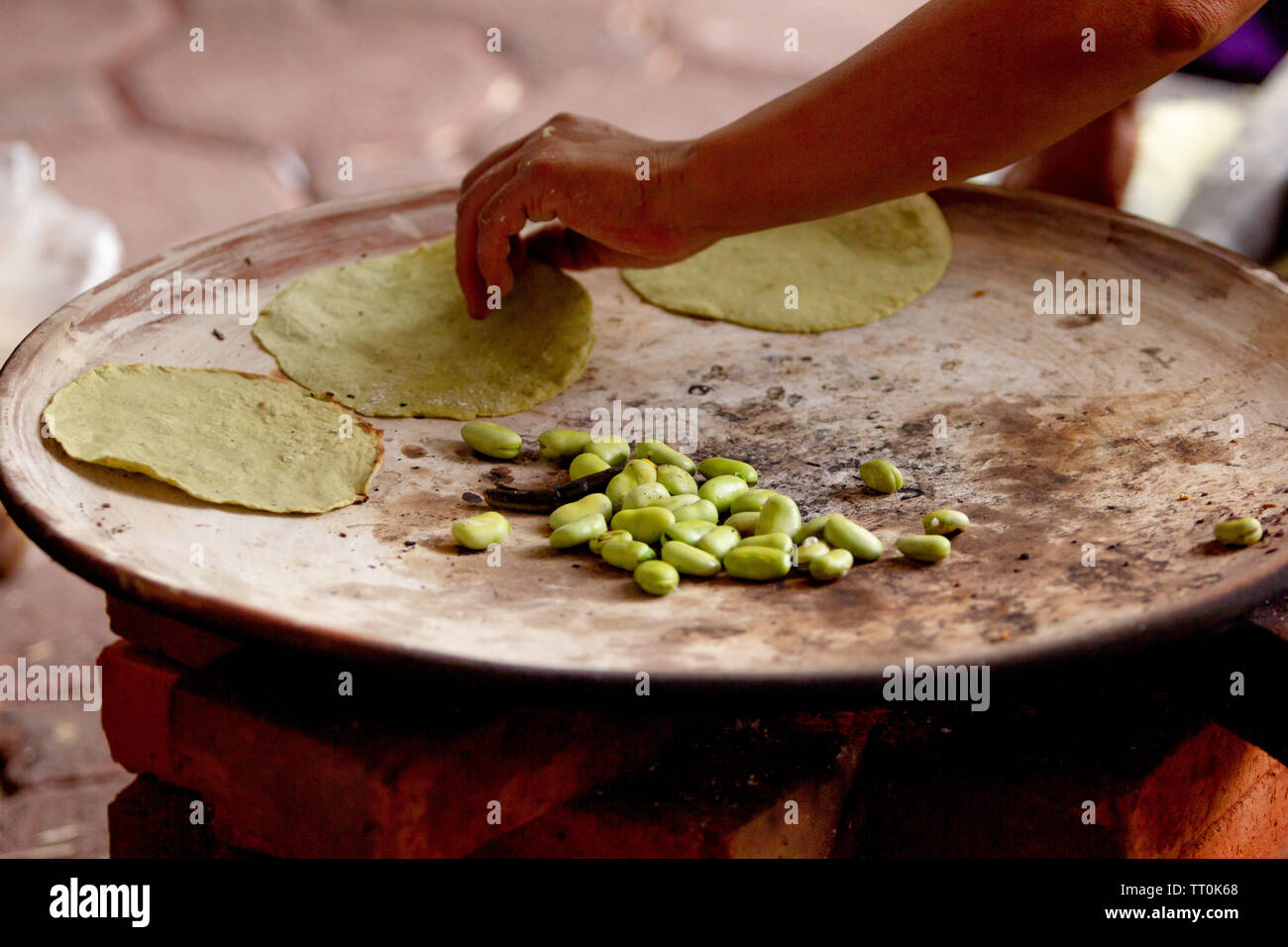 Eine Mexikanerin kochen Tortillas auf einer mexikanischen drei Stein Herd durch Holz- und Bohnen, ländliche Szene gefeuert Stockfoto