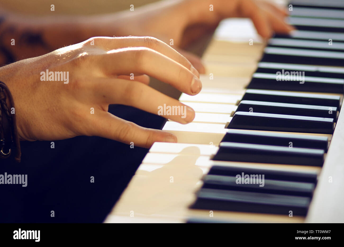 Auf eine musikalische Tasteninstrument, die von der Sonne beleuchtet wird, ein Mann spielt eine Melodie mit seinen Händen. An Hand der Armband tragen. Stockfoto