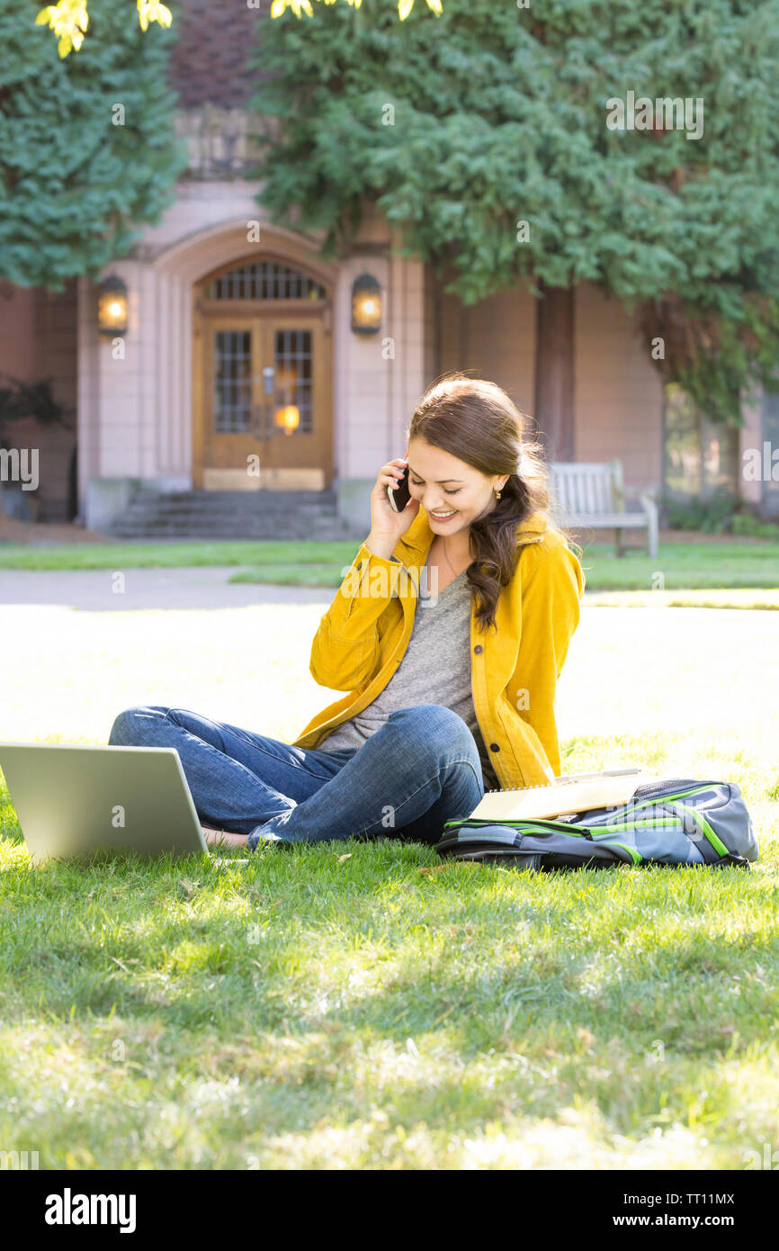 Glücklich lächelnd, junge Frau weibliche College Student mit Laptop telefonieren Handy im Freien auf dem Campus Stockfoto