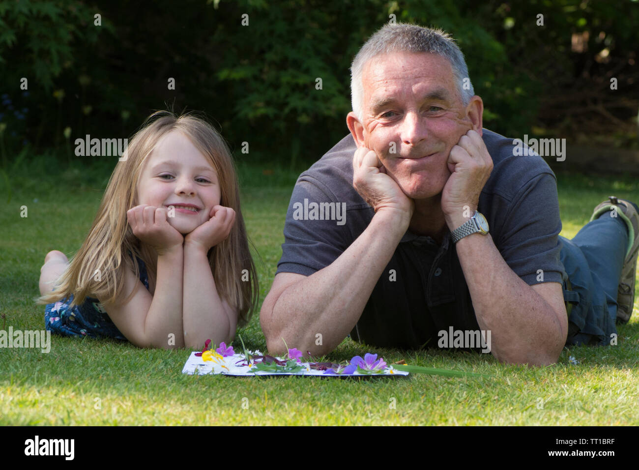 Drei Jahre alte Mädchen mit Großvater in Garten, durch ein Bild von Blumen und Blättern auf Papier geklebt, Posing, Natur Kunst Handwerk, schauen, glücklich Stockfoto