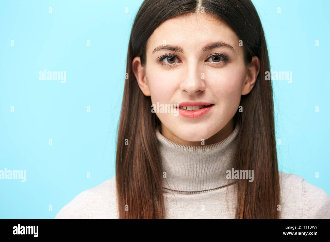 Porträt einer schönen jungen kaukasischen Frau, Kopf geschossen, in die Kamera lächeln suchen, auf blauem Hintergrund isoliert Stockfoto