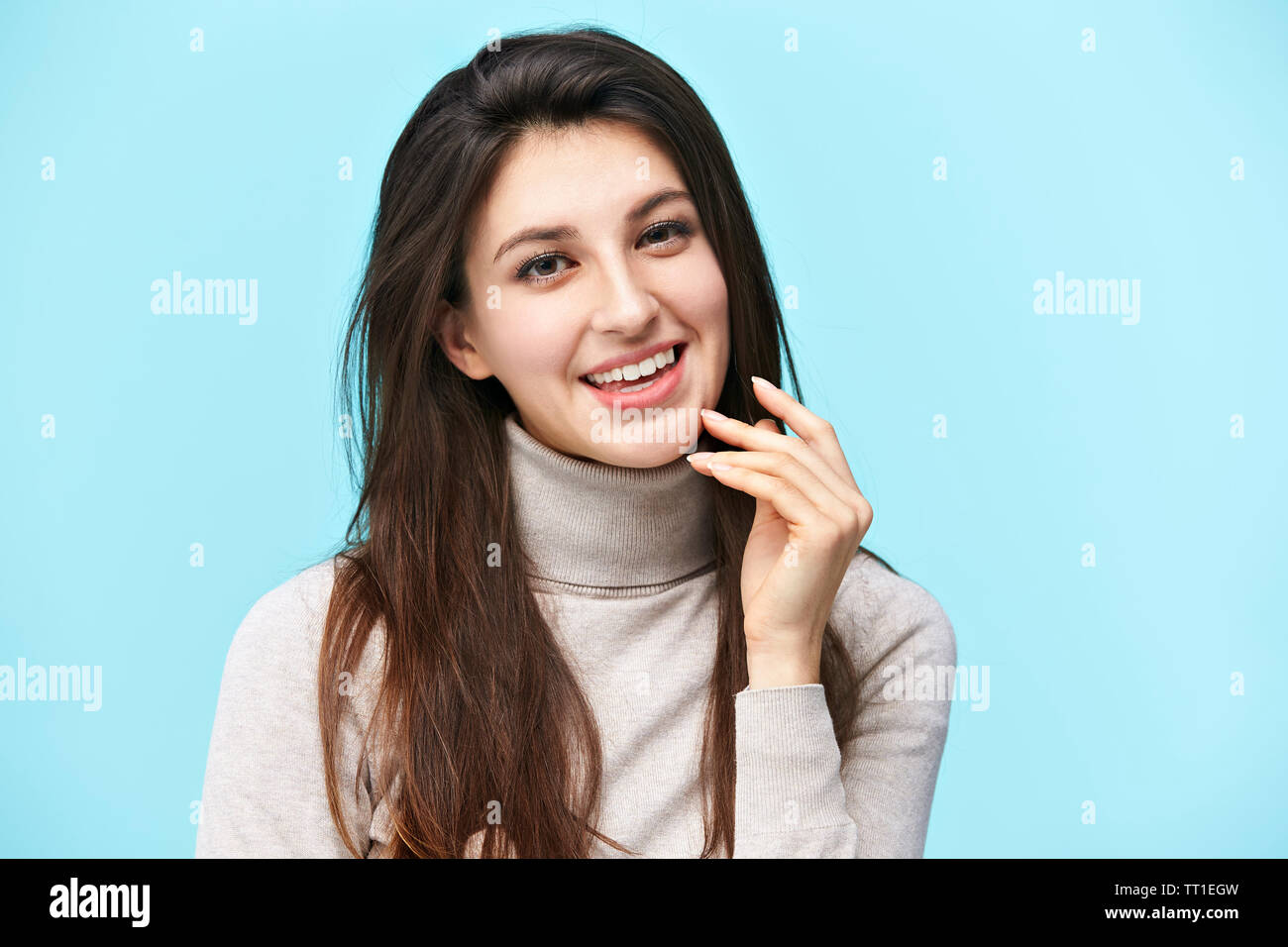 Porträt einer schönen jungen kaukasischen Frau, glücklich und lächelnd, an der Kamera suchen, auf blauem Hintergrund isoliert Stockfoto