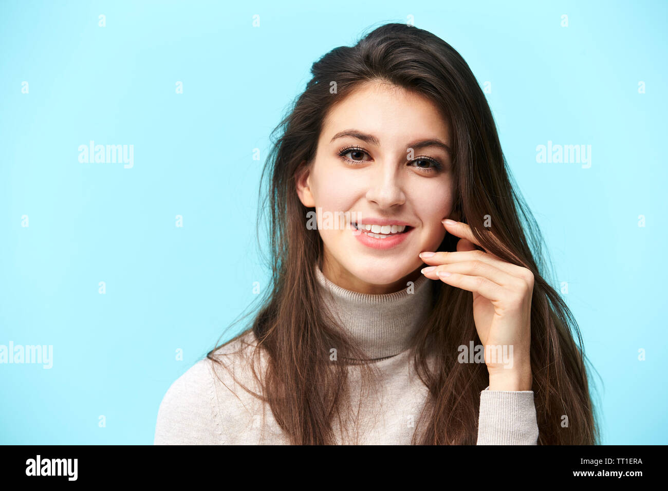 Porträt einer schönen jungen kaukasischen Frau, glücklich und lächelnd, an der Kamera suchen, auf blauem Hintergrund isoliert Stockfoto