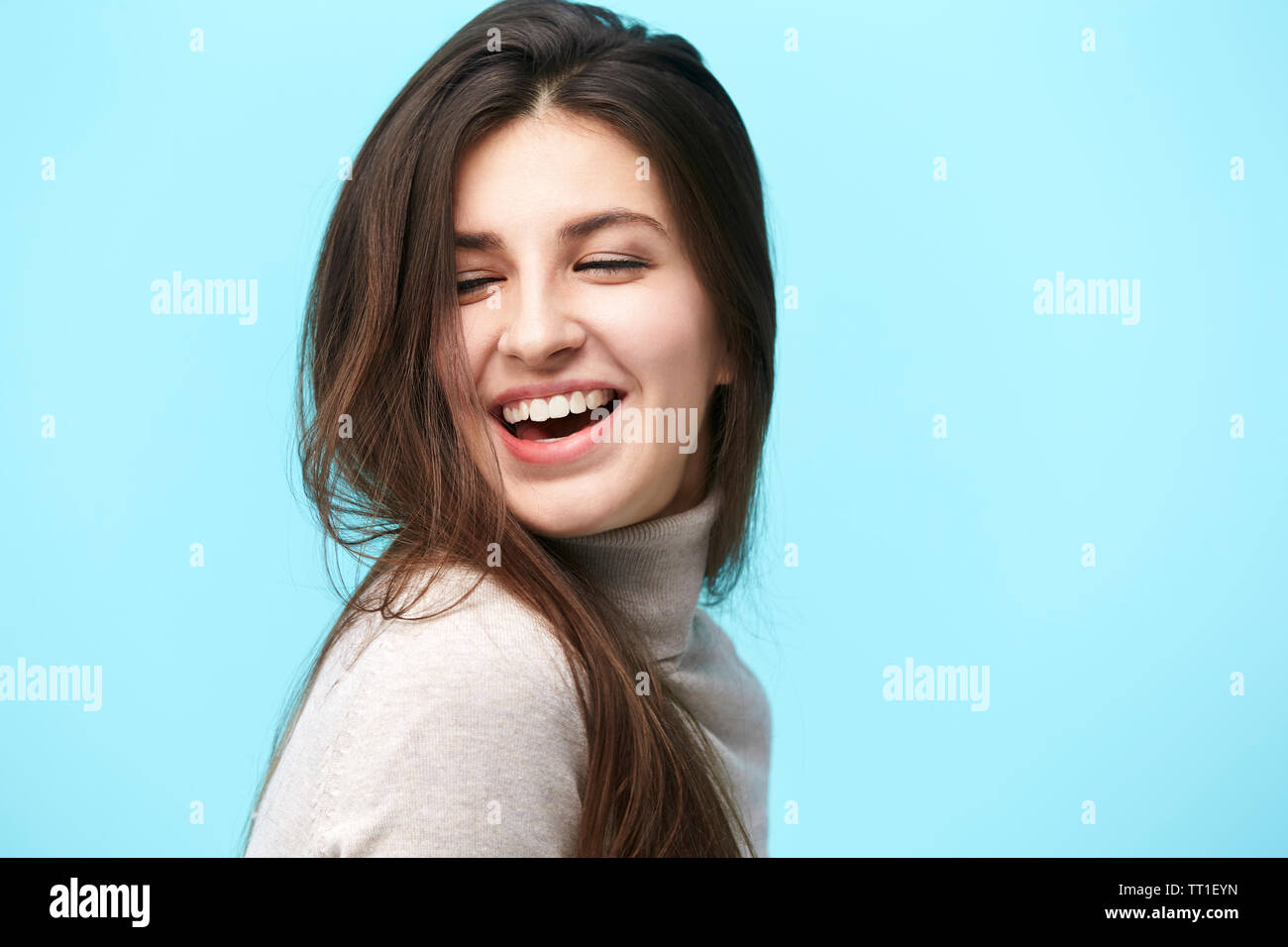 Portrait einer jungen kaukasischen Frau mit langem Haar, glücklich und lächelnd, auf blauem Hintergrund isoliert Stockfoto