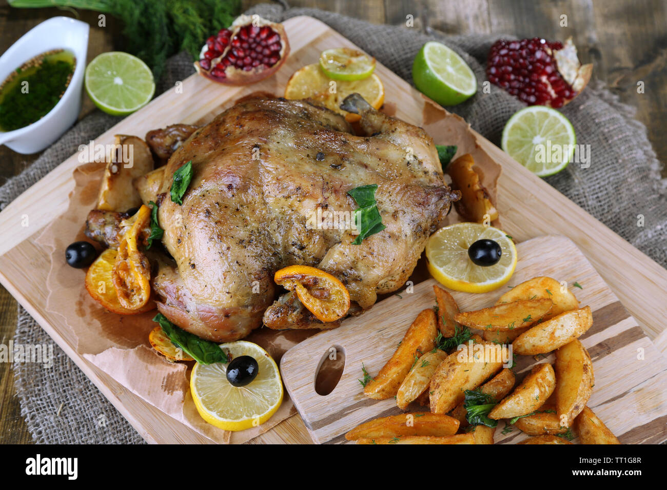 Ganzen gebratene Hähnchen mit Gemüse und Bratkartoffeln auf Holzplatte ...