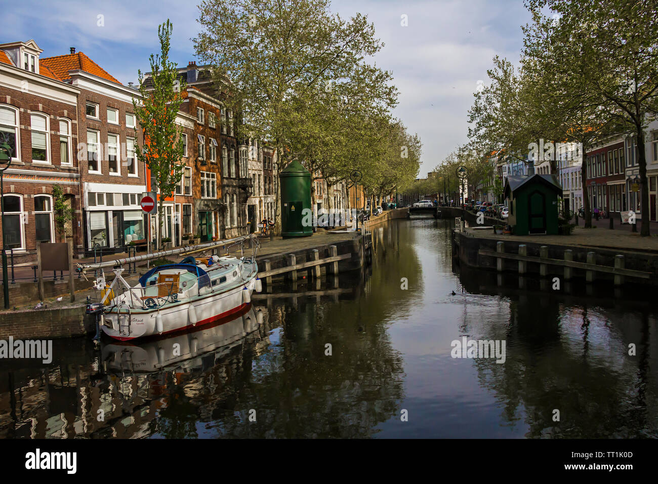 Gouda, Holland, Niederlande, April 23, 2019, Fahrräder und in der Nähe einer Brücke entlang einer Straße geparkt, Canal in Gouda Altstadt. Blumen in einem blumenbeete, Boot Stockfoto