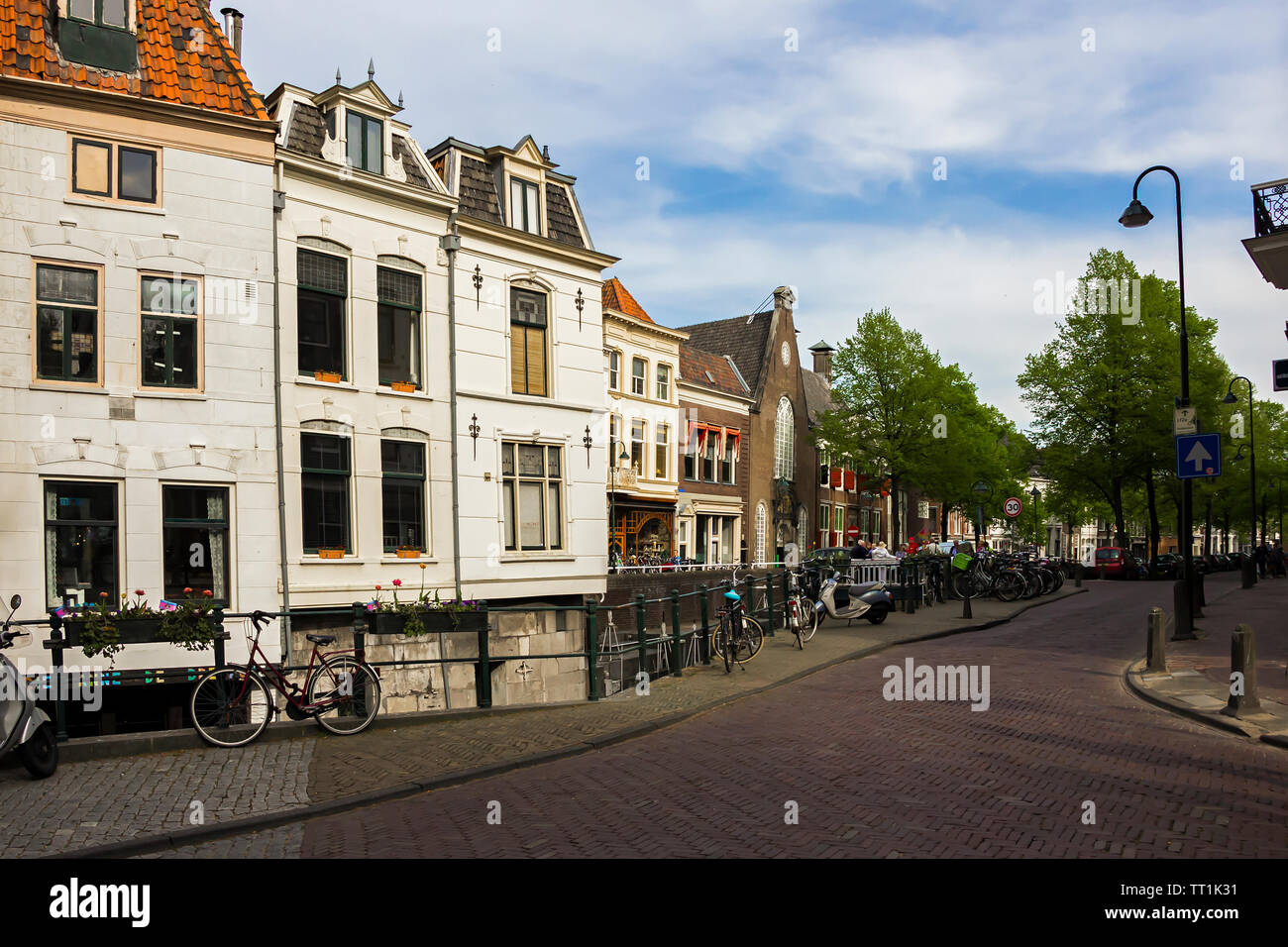 Gouda, Holland, Niederlande, April 23, 2019, Fahrräder und in der Nähe einer Brücke entlang einer Straße geparkt, Canal in Gouda Altstadt. Blumen in einem blumenbeete, Boot Stockfoto