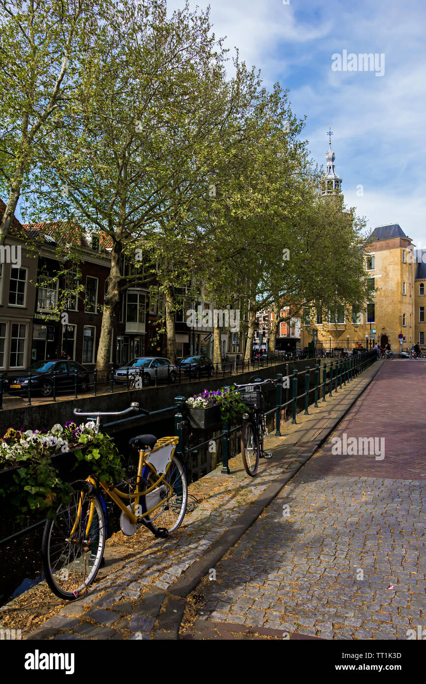 Gouda, Holland, Niederlande, April 23, 2019, Fahrräder und in der Nähe einer Brücke entlang einer Straße geparkt, Canal in Gouda Altstadt. Blumen in einem blumenbeete, Boot Stockfoto