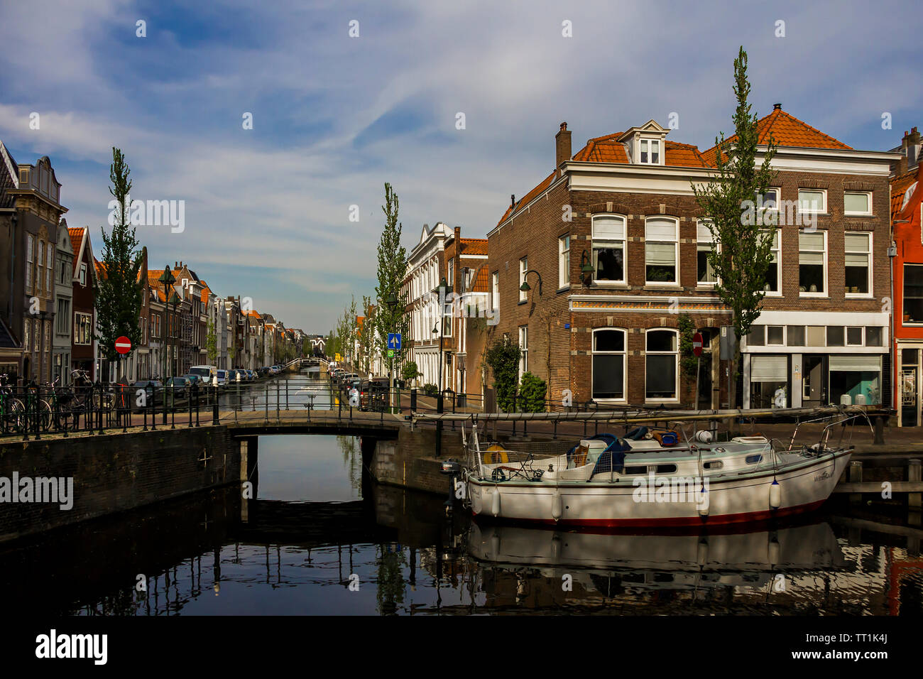 Gouda, Holland, Niederlande, April 23, 2019, Fahrräder und in der Nähe einer Brücke entlang einer Straße geparkt, Canal in Gouda Altstadt. Blumen in einem blumenbeete, Boot Stockfoto