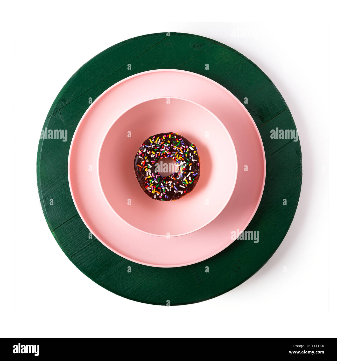 Grafische Darstellung eines einzigen Donut in rosa Essgeschirr auf einem grünen Holz- Oberfläche Stockfoto