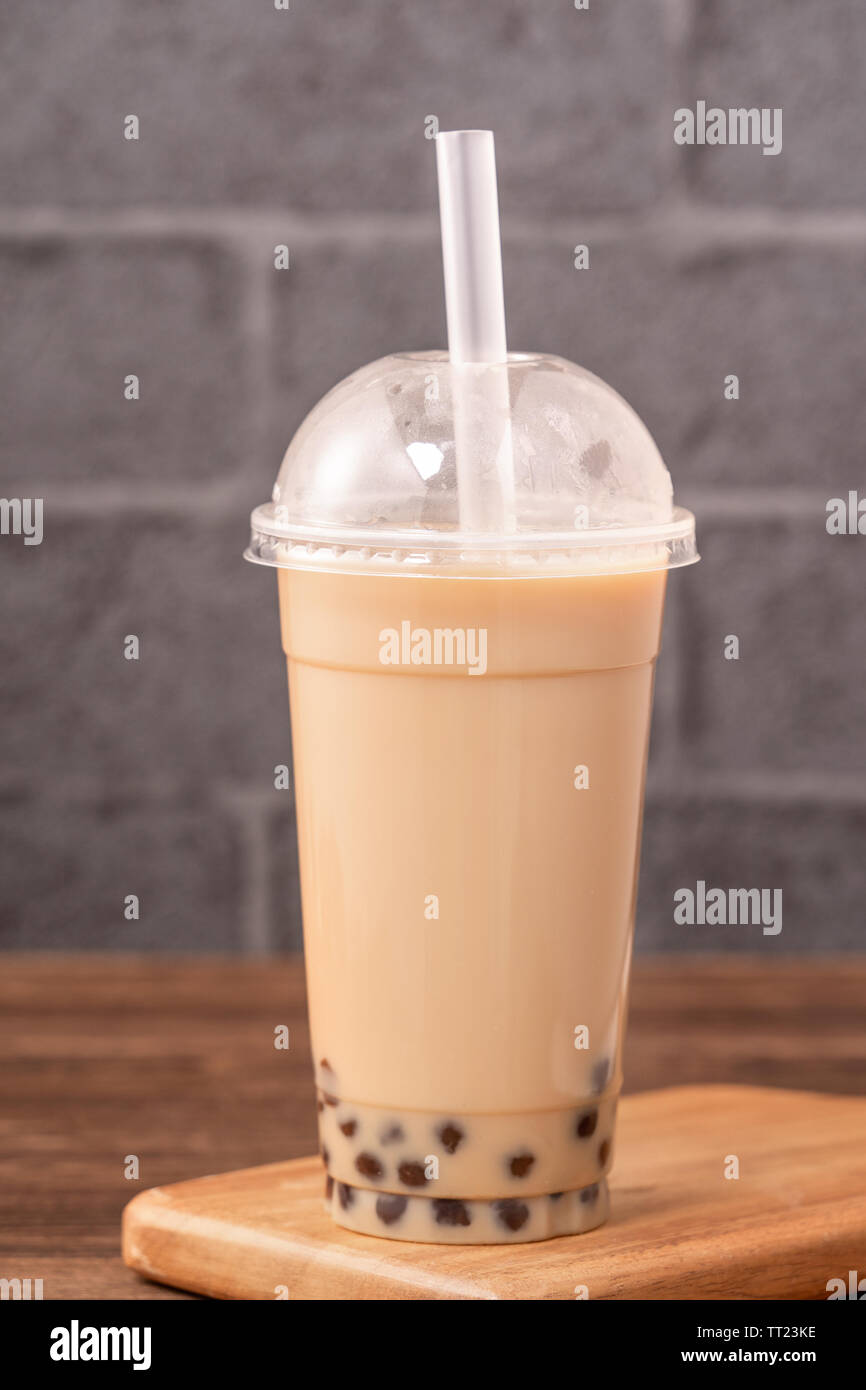 Takeout mit Einweg los Konzept beliebt Taiwan bubble Milch trinken Tee mit Schale aus Kunststoff und Stroh auf Holztisch, Hintergrund, Nahaufnahme, kopieren Raum Stockfoto