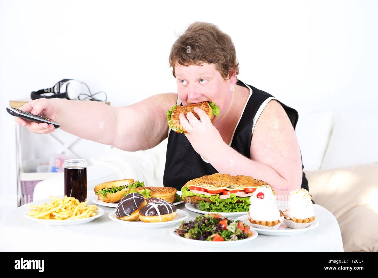 Fat Man hat ein großes Mittagessen und Fernsehen, auf Home Interior Hintergrund Stockfoto