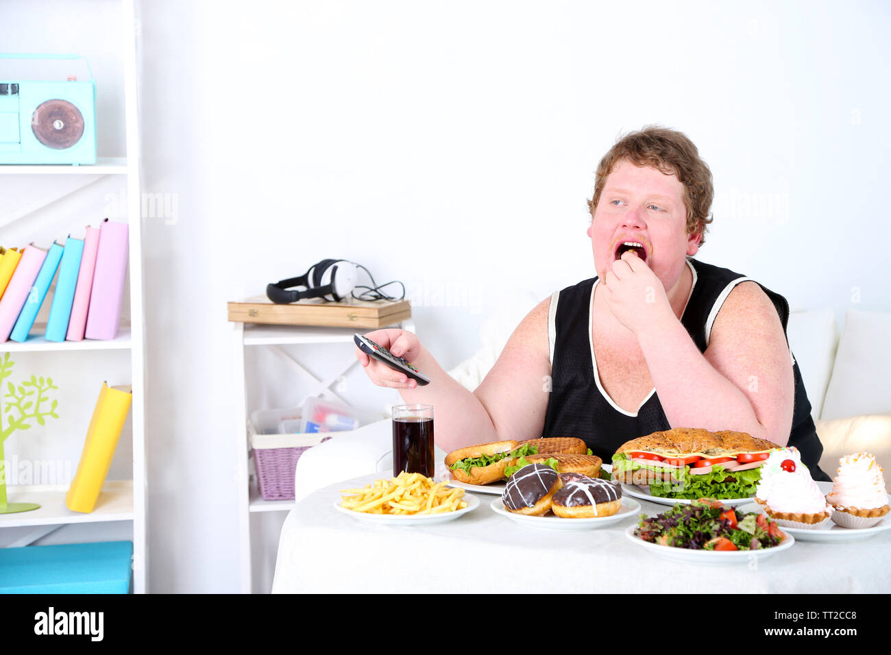 Fat Man hat ein großes Mittagessen und Fernsehen, auf Home Interior Hintergrund Stockfoto