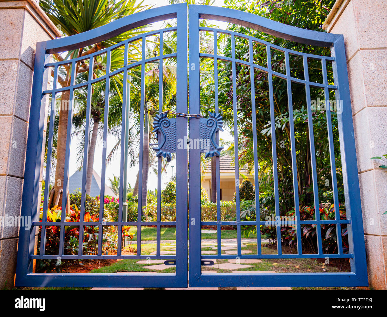 Antike Stahl blau double Gate mit Vorhängeschloss vor einem tropischen Garten in einem Erholungsort - Low Angle Shot Stockfoto
