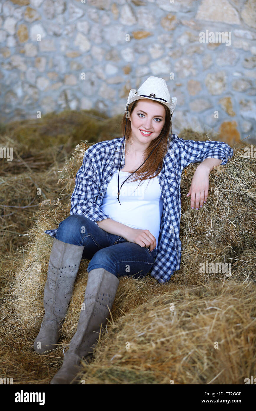 Schöne cowgirl Modell posiert im Heu auf landwirtschaftlich genutzten Flächen. Stockfoto
