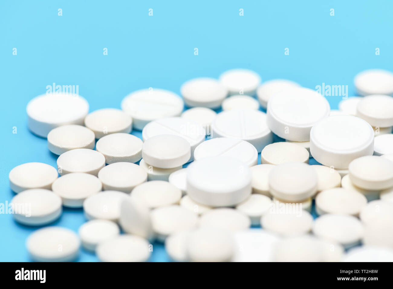 Close-up viele Weiße, runde Tabletten auf blauem Hintergrund. Medizinischer Hintergrund Stockfoto