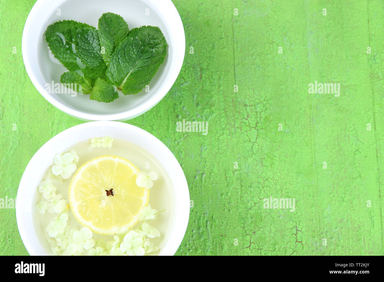 Schalen mit Blumen und parfümierten Wasser auf Holz- Hintergrund Stockfoto