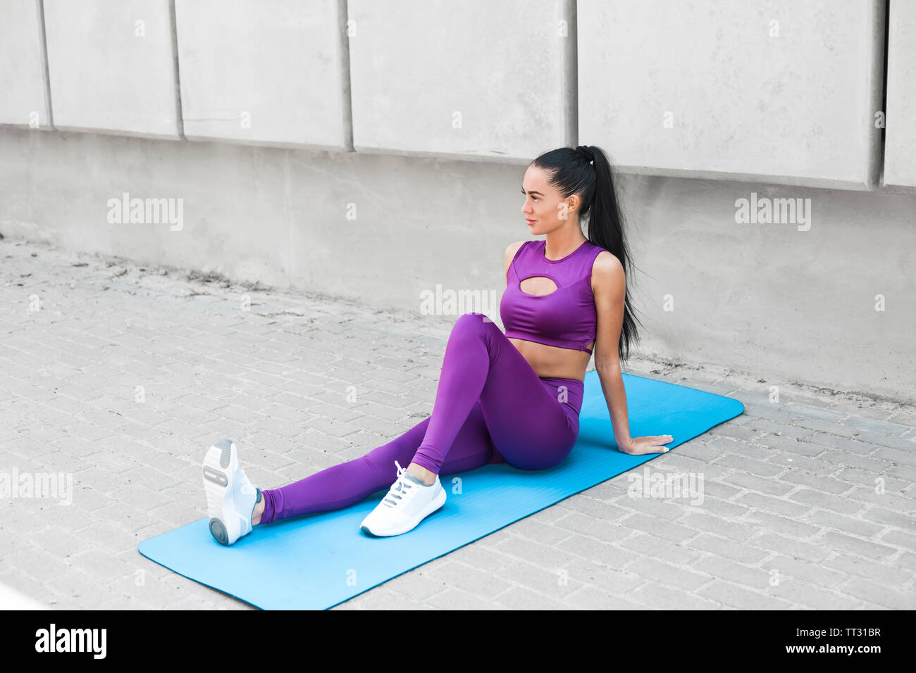 Porträt einer sportliche junge Frau in stilvollen Leggings. Stilvolle Fitness Mädchen auf grauem Hintergrund die Straßen der Stadt. Stockfoto