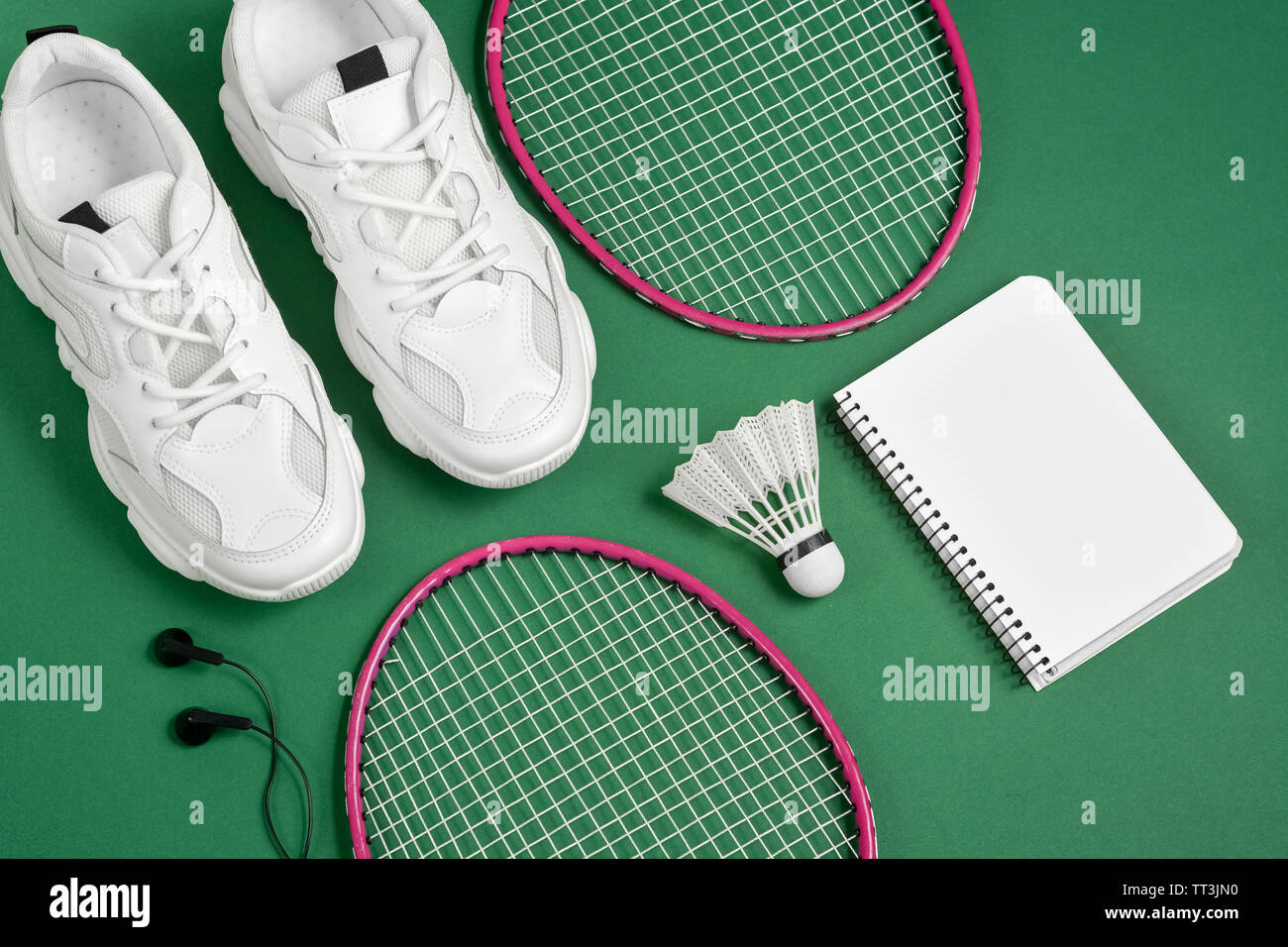 Sportgeräte. Federball und Badminton Schläger, Turnschuhe, Kopfhörer, Stift und Notizblock auf grünem Hintergrund. Fitness und gesunde Lebensweise. F Stockfoto
