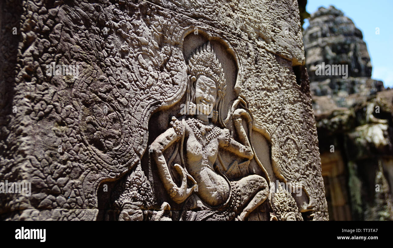 Detail eines antiken Skulptur mit einer unscharfen Stein Turm im Hintergrund in der schönen Bayon Tempel - eine dekorierte Khmer Tempel. (Angkor Wat, UNE Stockfoto