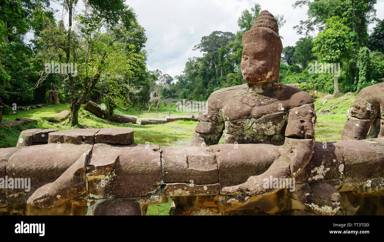 Eine Statue mit ruiniert Gesicht halten der Zaun von der Straße außerhalb der antiken Stadt der Khmer Imperiums - Angkor Thom. (Angkor Wat, Siem Reap, Kambodscha). Stockfoto