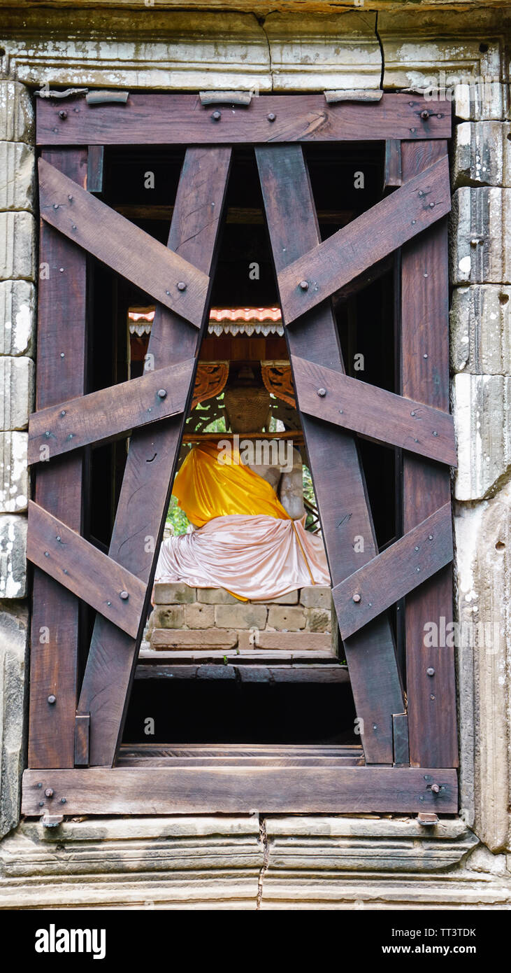 Eine seltene Schuß von der Zurück-Gate in Bayon Tempel auf der Rückseite des Buddha Statue in orange Tuch mit symmetrischen Holz- Barrieren. (Angkor Wat, Siem Reap Stockfoto