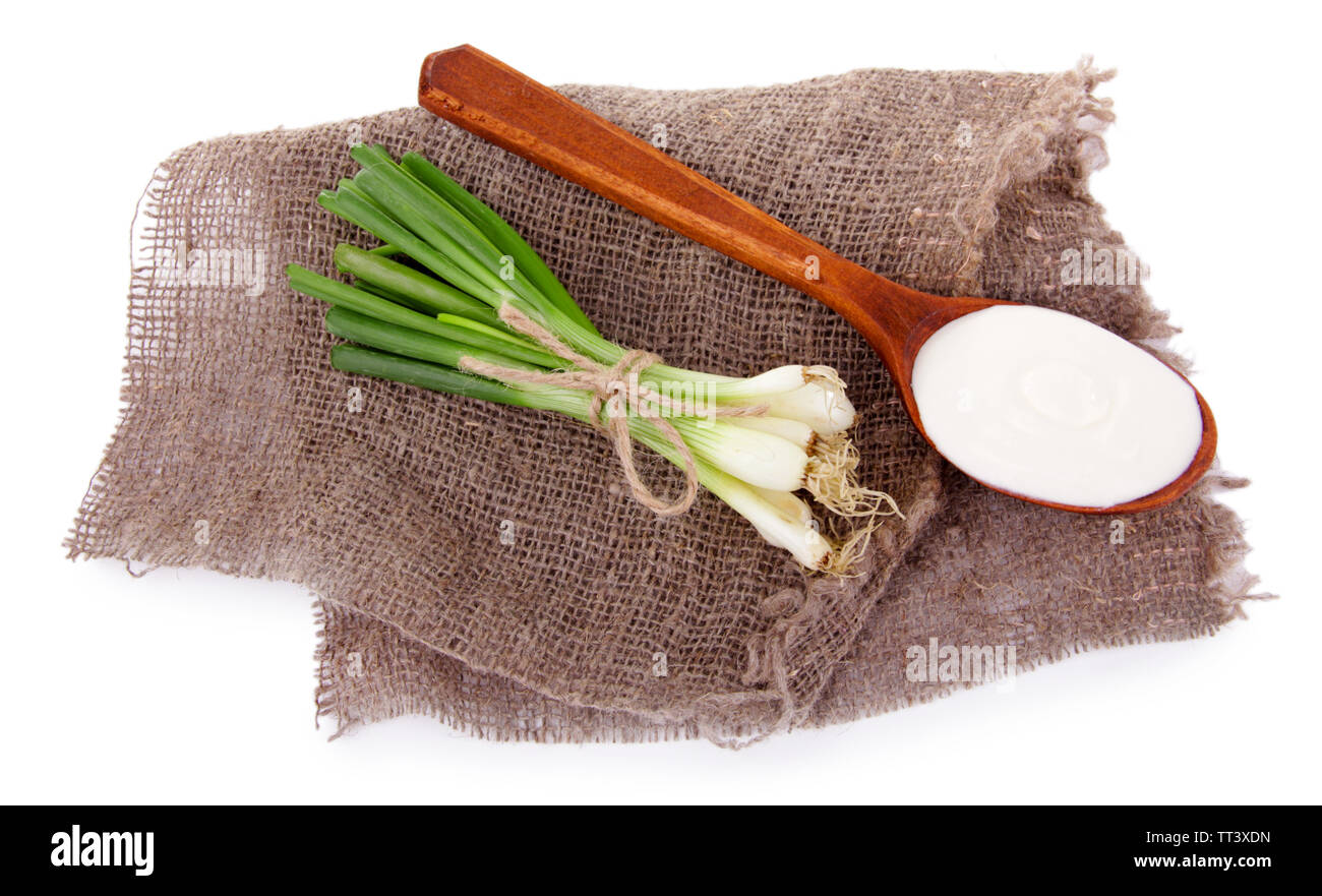 Holzlöffel Creme und ein Büschel von Zwiebel am Stück Sackleinen auf weißem Hintergrund Stockfoto