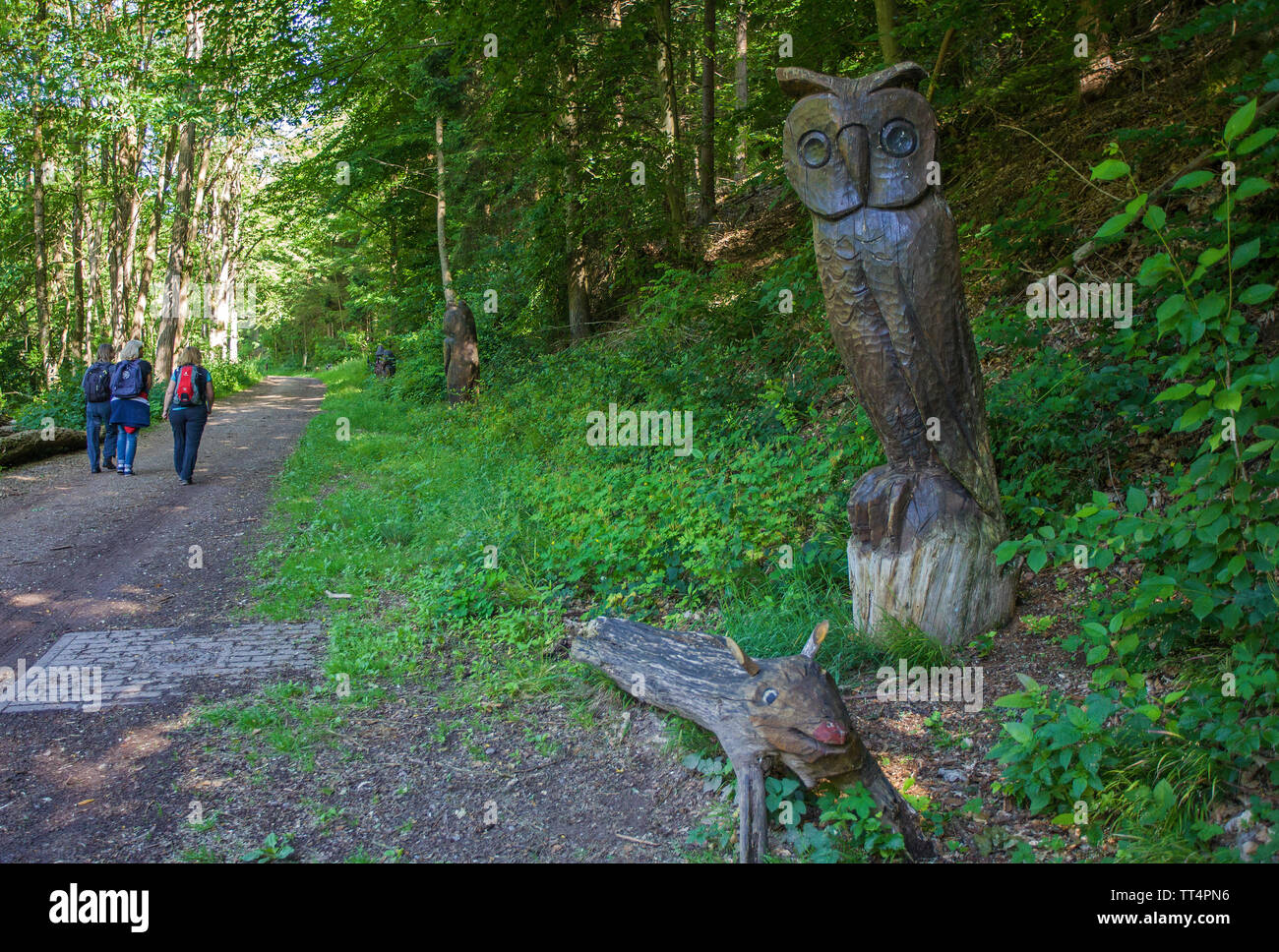 Geschnitzte Eule auf einem Baumstamm, Wanderer im Wald Geister Trail (deutsch: Waldgeisterweg), Oberotterbach, Deutsche Weinstraße, Rheinland-Pfalz, Deutschland Stockfoto