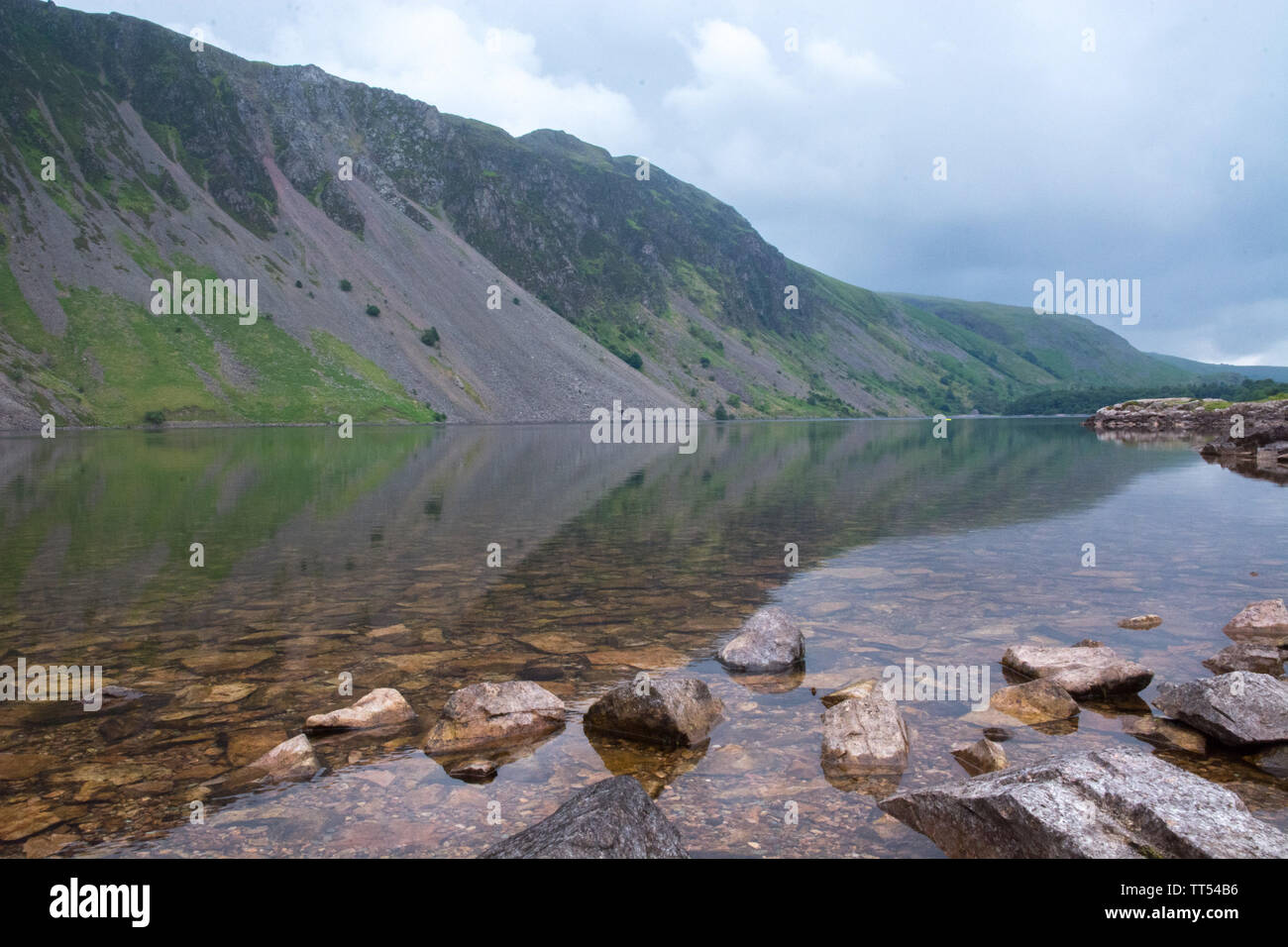 Relection der Berge im eiskalten Wasser des Cumbrian Lakes. Felsen im Vordergrund Perspektive geben. Stockfoto