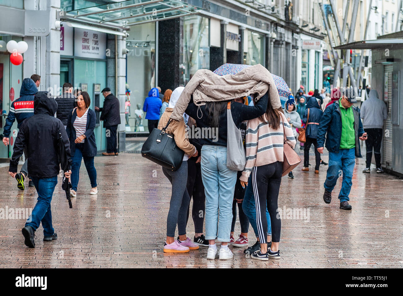 Cork, Irland. Juni 2019. Eine Gruppe von Freunden kuscheln sich zusammen, um an einem nassen Tag auf der Patrick Street im Stadtzentrum von Cork trocken zu bleiben. Quelle: AG News/Alamy Live News. Stockfoto