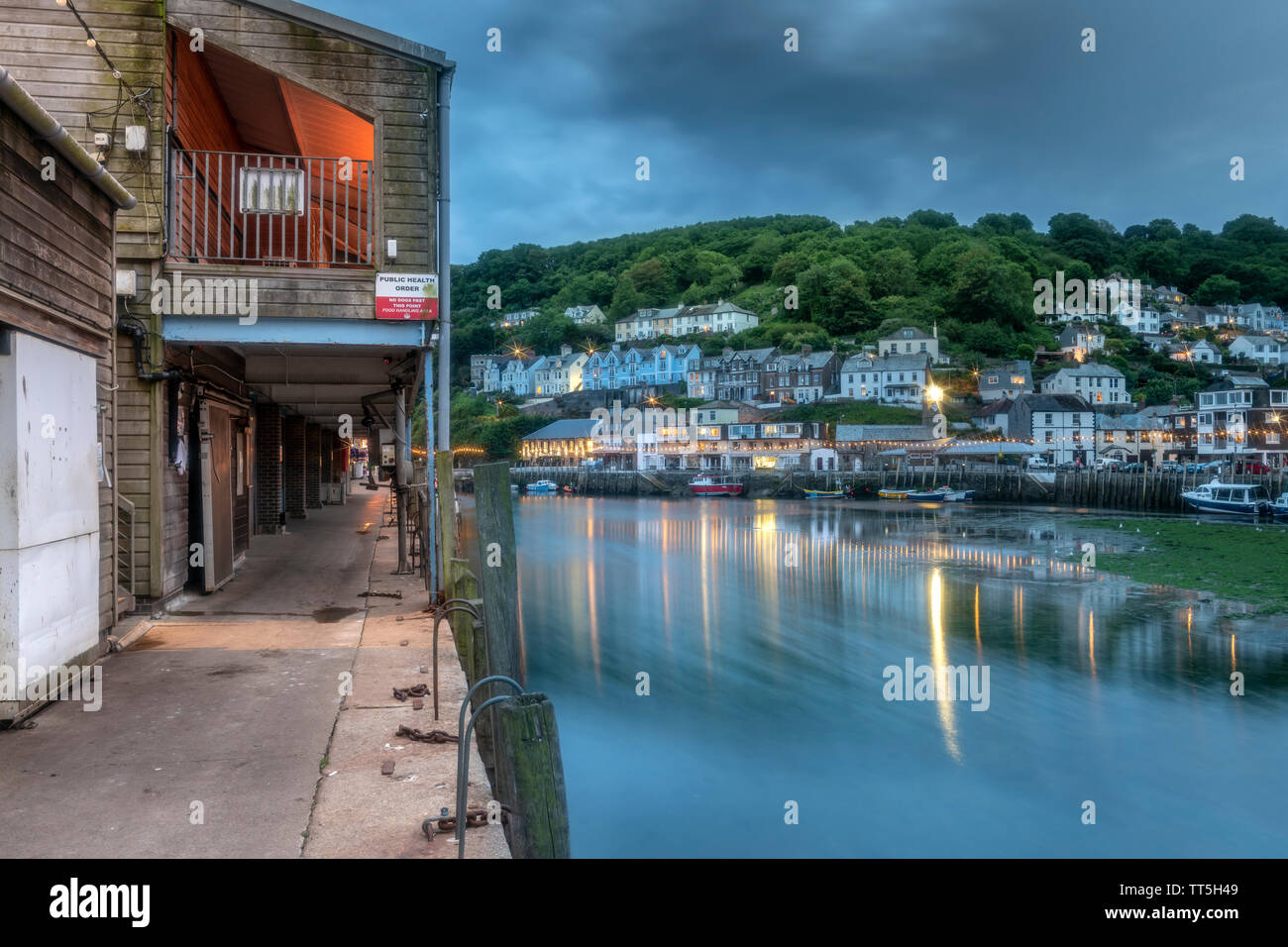 Nach dem anderen kühlen bewölkten Tag die Lichter flackern auf wie das Tageslicht in der Dämmerung in der historischen Fischerhafen von Looe, Cornwall. Stockfoto