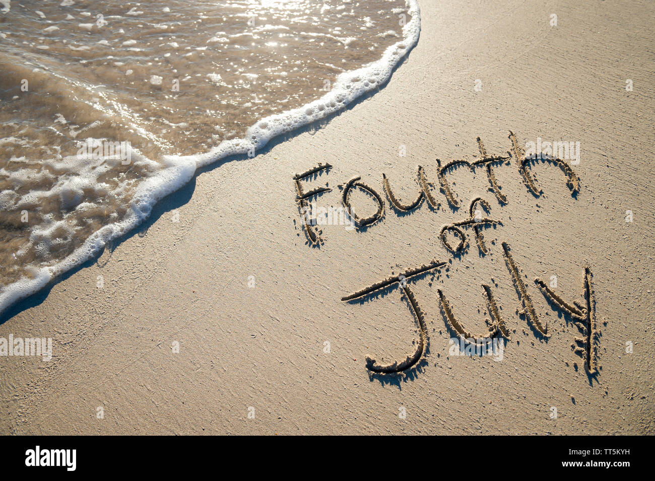 Am 4. Juli Nachricht für den amerikanischen Unabhängigkeitstag Urlaub in sanften Sand mit ankommenden Welle am Strand geschrieben Stockfoto