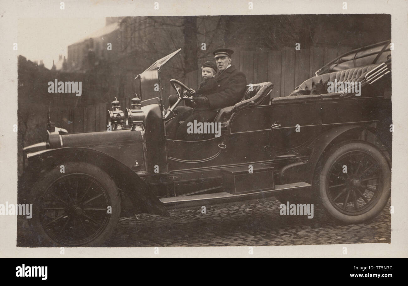 Vintage Edwardian photographische Postkarte eines britischen Chauffeur, junge Schule Junge und ein Cat Reiten in einem klassischen Automobils. Im Dezember 1909 berücksichtigt. Stockfoto
