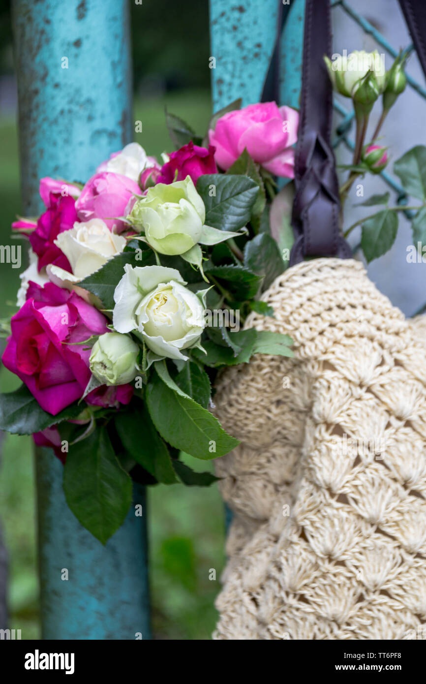 Blumenstrauß aus duftenden Englisch rosa und weißen Rosen in einer Tasche aus Bast hängt am Zaun Stockfoto