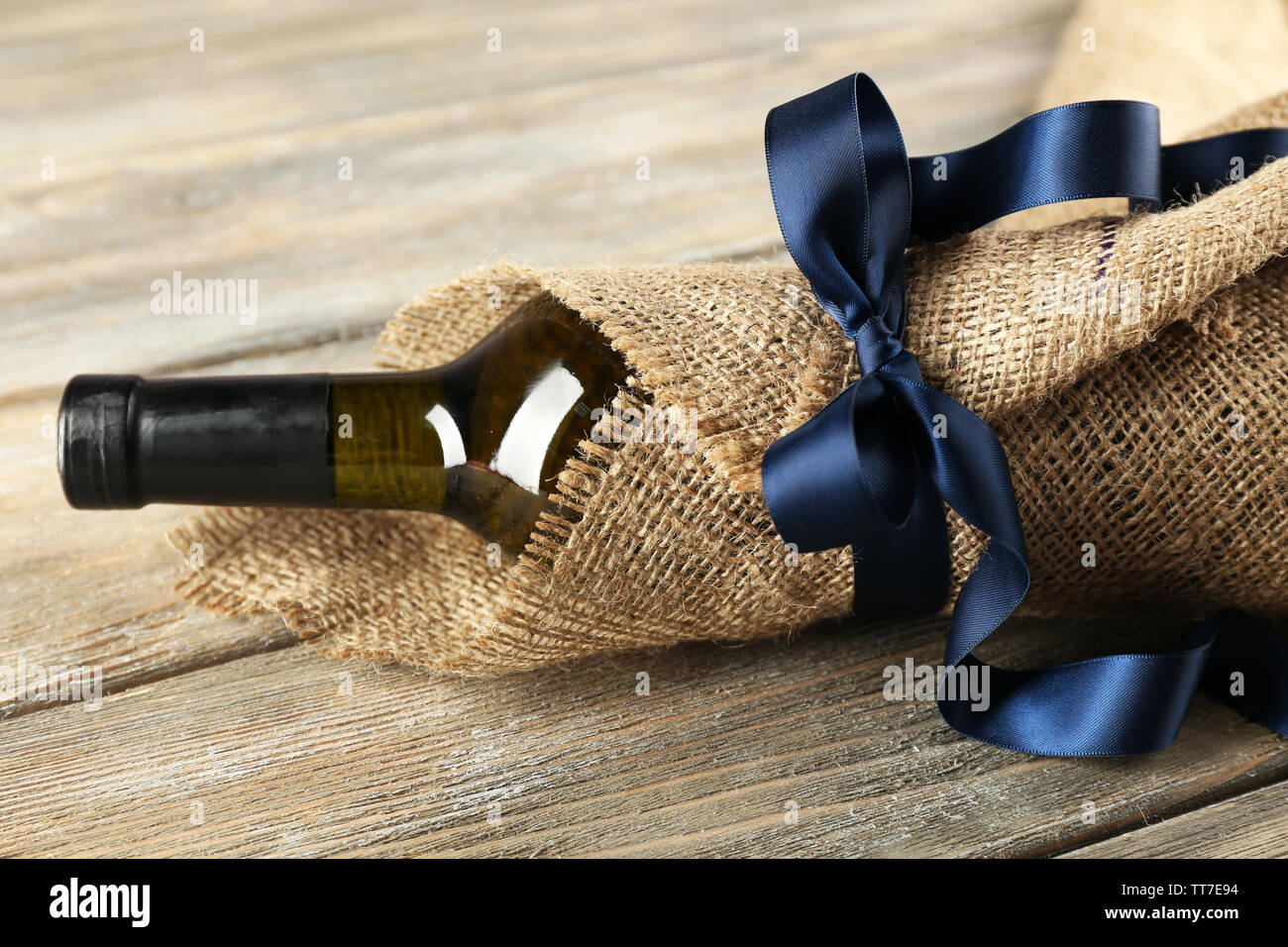 Flasche Wein in sackleinen Tuch auf Holzbohlen Hintergrund gewickelt Stockfoto