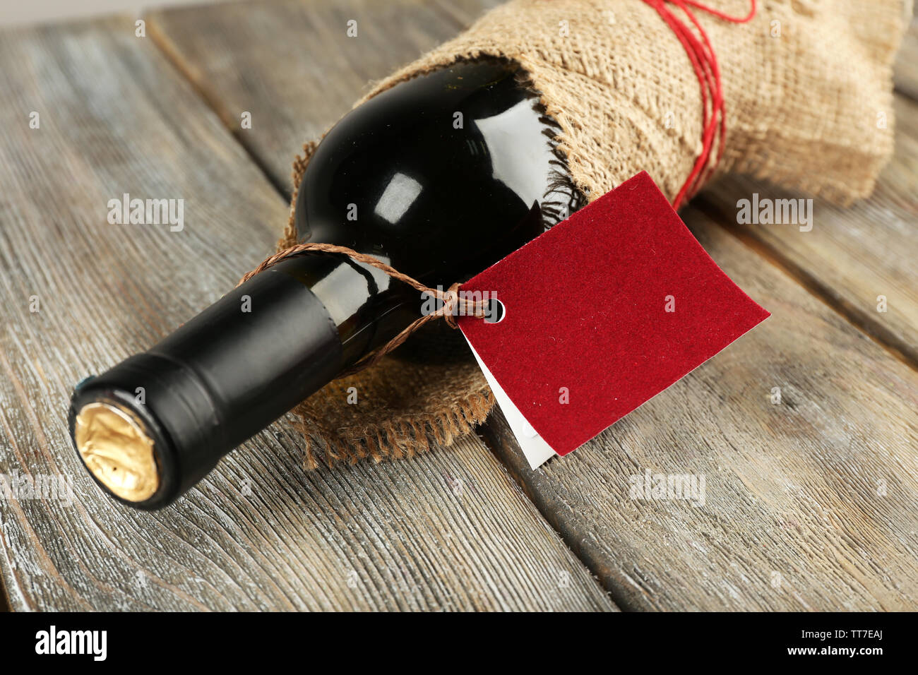 Flasche Wein in sackleinen Tuch auf Holzbohlen Hintergrund gewickelt Stockfoto