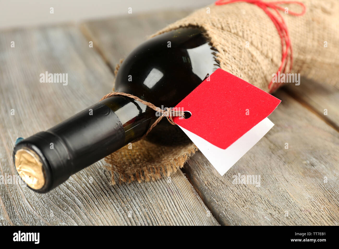 Flasche Wein in sackleinen Tuch auf Holzbohlen Hintergrund gewickelt Stockfoto