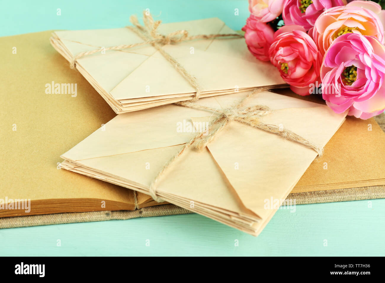 Alte Briefe und Buch mit Blumen auf Holz- Hintergrund Stockfoto
