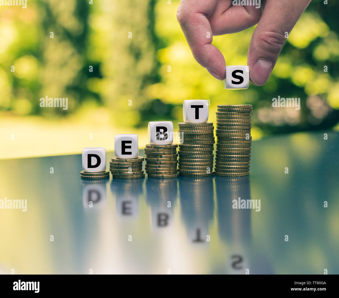 Symbol für die Erhöhung der Schulden. Würfel Form das Wort Schulden auf die Steigerung der hohen Stapel von Münzen 'd'. Stockfoto