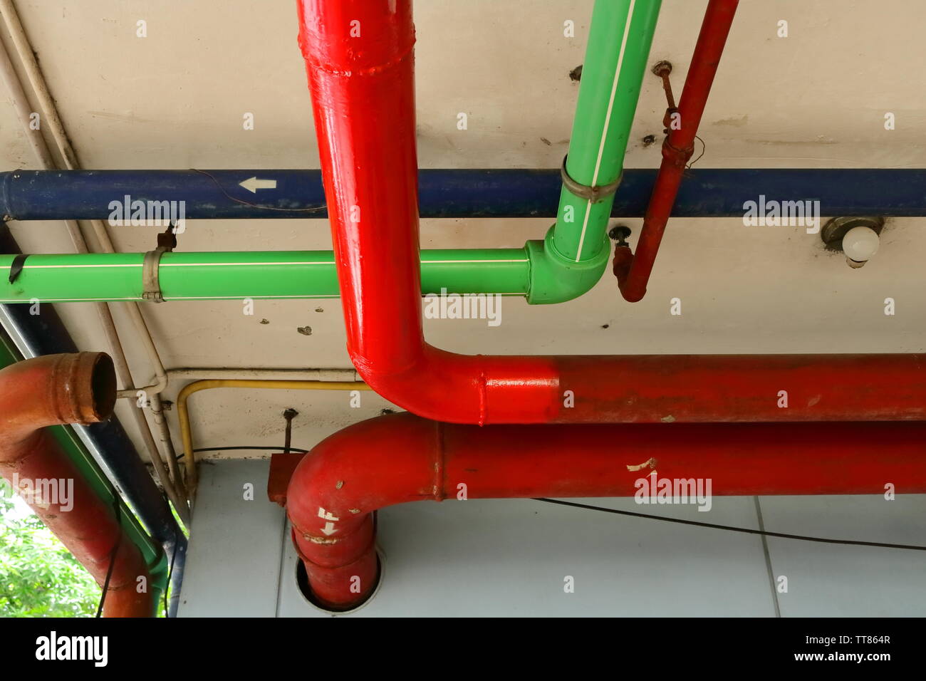 Nahaufnahme von roten, grünen und blauen Leitungen laufen unter der Decke eines Gebäudes Stockfoto