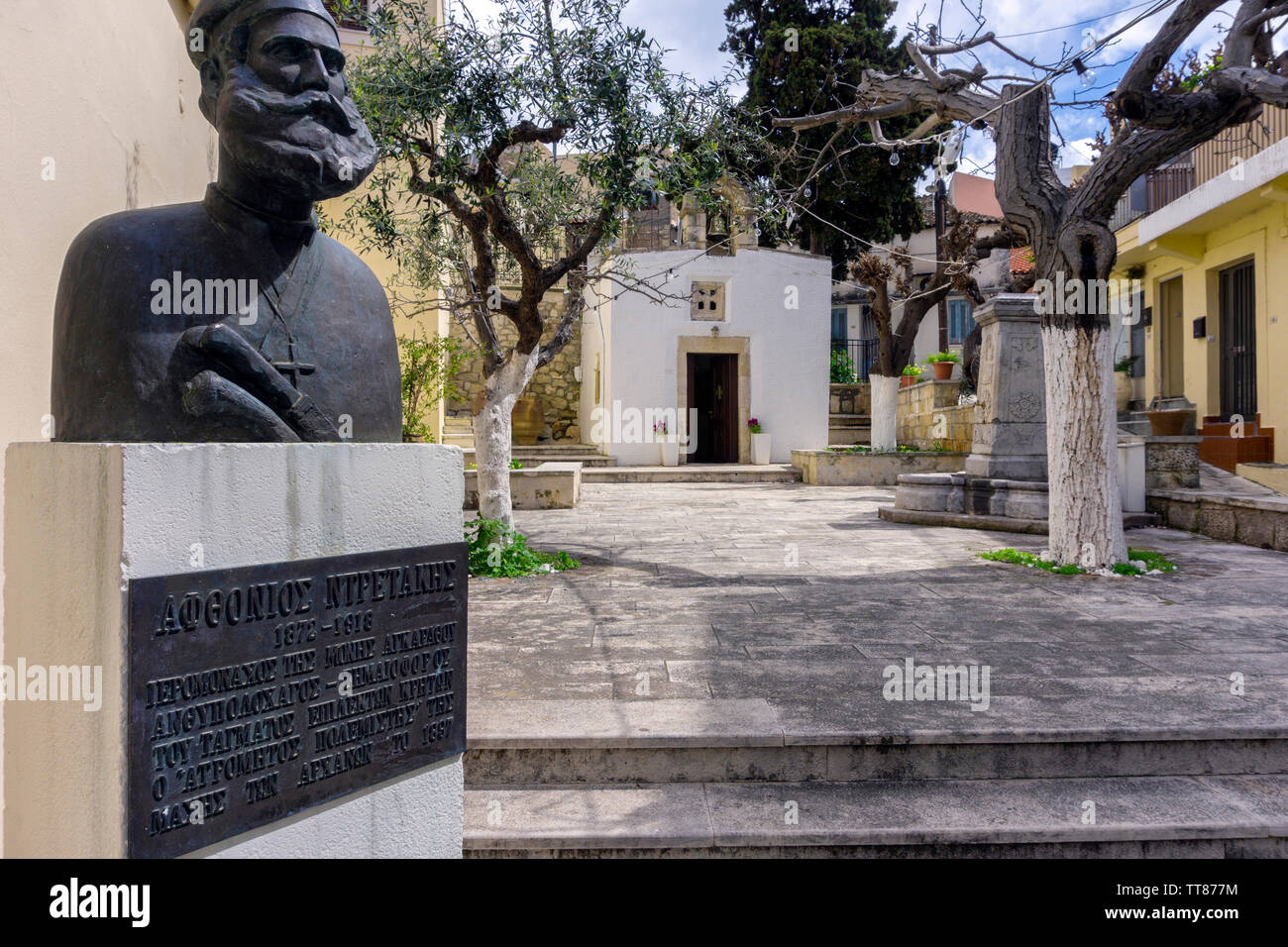 Chersonissos, Kreta/Griechenland. Die "Heilig-Kreuz-Kapelle" in Archanes Stadt. Stein Brunnen im Innenhof, die Statue eines kretischen Held Stockfoto