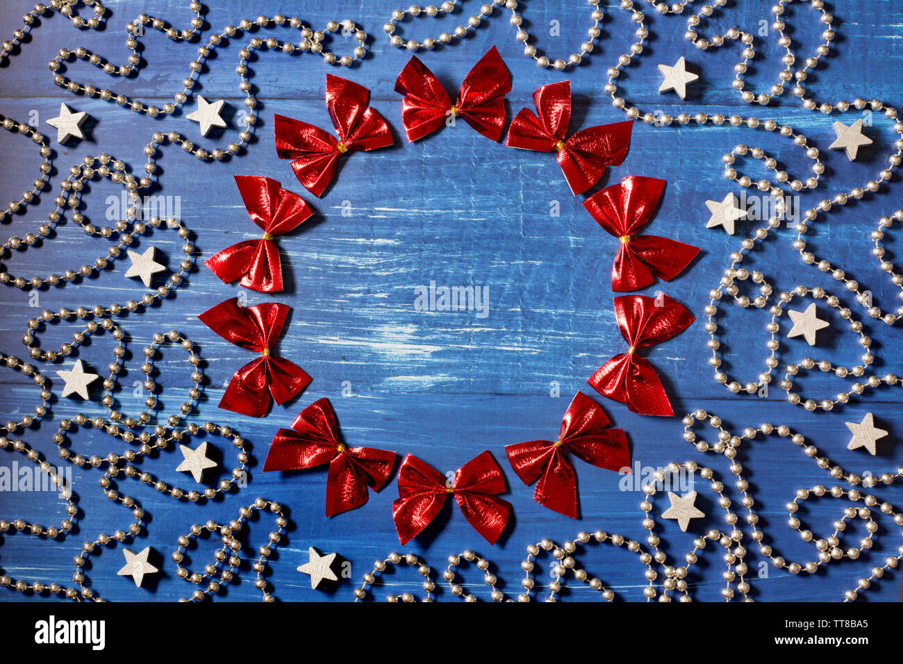 Weihnachtsdekoration mit einem cirle der roten Bändern, Silber Perlen Kette und Sterne auf dunkelblauem Hintergrund Holz - Platz für Text, tiefe Schatten Stockfoto
